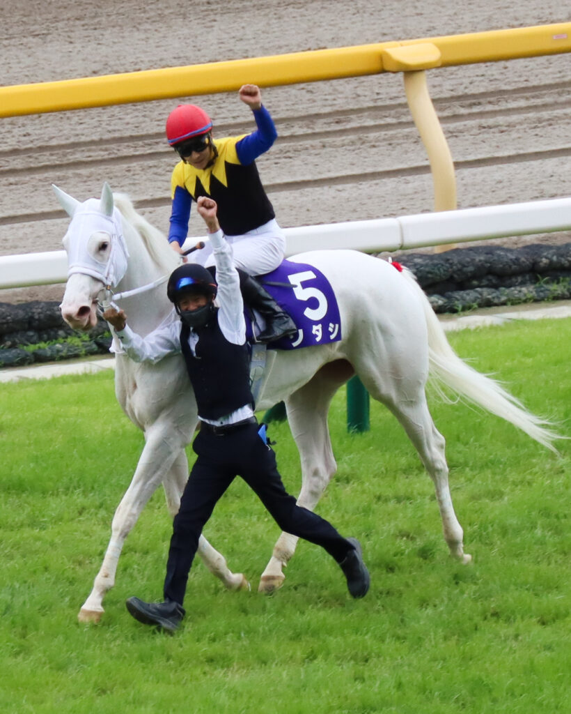 勝利の喜びを分かち合う白毛の女王ソダシと、左手を掲げ駆け寄る今浪厩務員と吉田隼人騎手。ヴィクトリアマイル2022年のウイニングラン