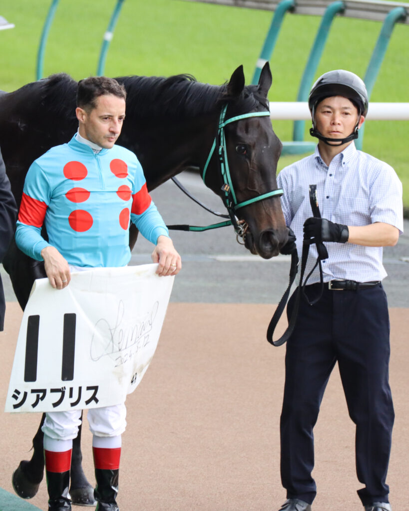 2024年5月12日東京競馬場の未勝利戦を勝利し、ウイナーズサークルでルメール騎手と並ぶ出資馬シアブリスの記念写真