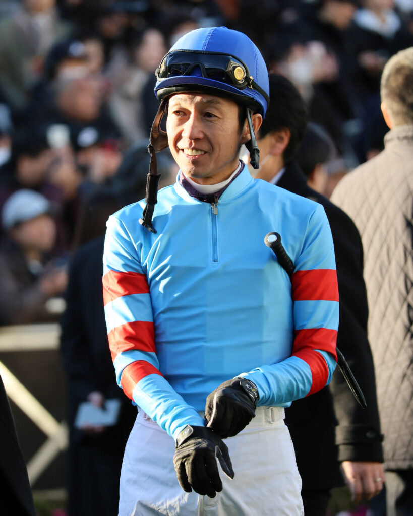 2024年12月28日ホープフルステークス、中山競馬場のパドックで笑顔で馬に歩み寄る武豊騎手の写真