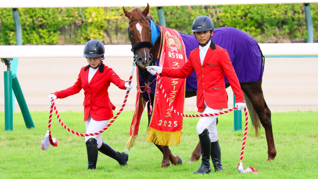 深紅のレイを掛けて静かに立つウインカーネリアン。その眼差しはどこか誇らしげで、GⅠ馬としての風格がにじみ出ていた。