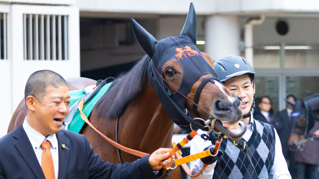 2025年ターコイズステークス（GⅢ）中山競馬場のパドックで、出資馬チェルビアットを囲み笑顔を見せる高野調教師と厩務員。和やかな雰囲気が伝わる一枚。